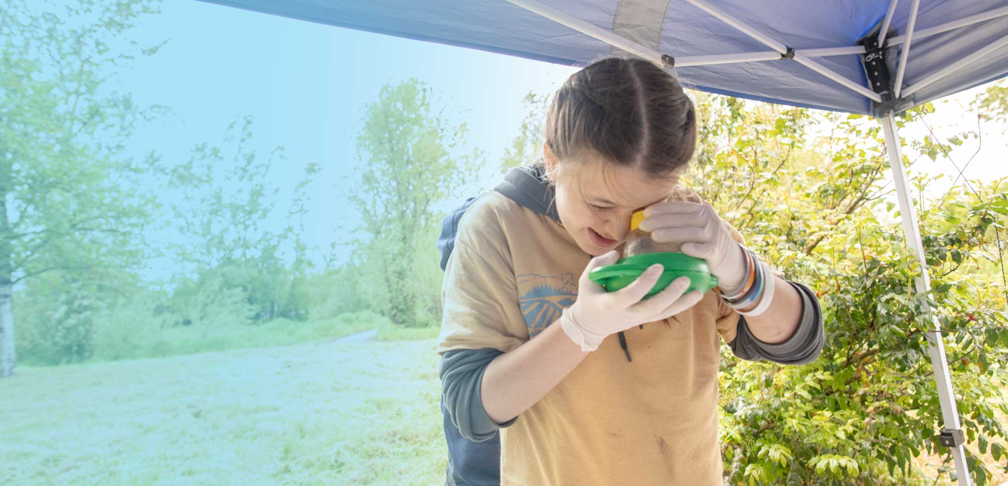 student looks through hand magnifier at stonefly